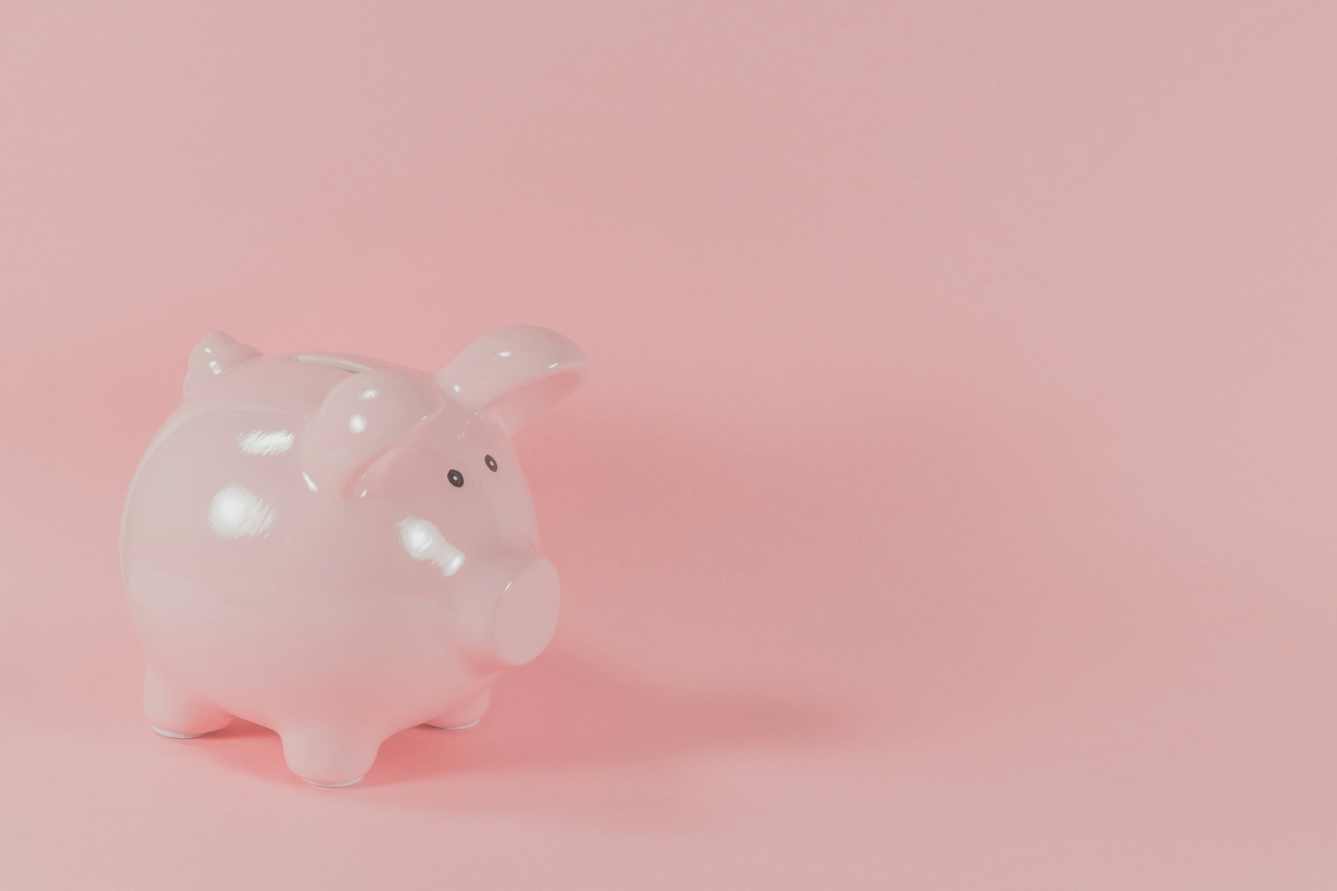 ピンクの背景に置かれた豚の貯金箱